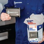 Person holding Elecbrakes VM1 unit beside open VM1 retail box