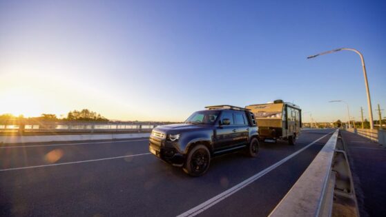 4WD towing a caravan on a bridge at sunrise