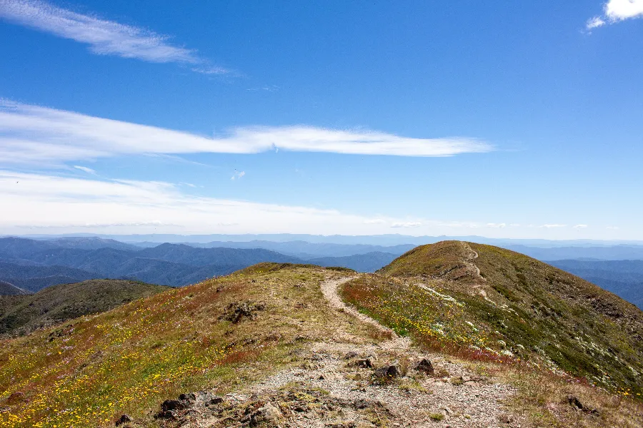 Hiking trail along a mountain ridge, blue sky.