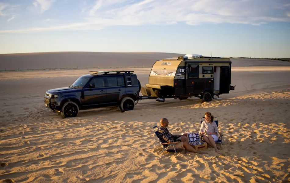 Travellers enjoying the beach, with their trailer and car.